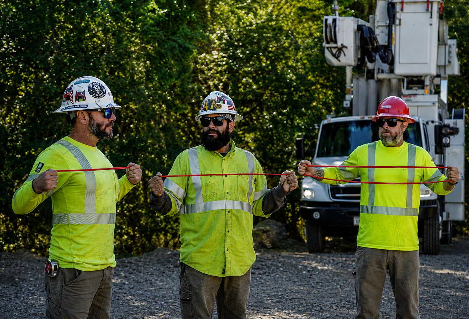 Three utility workers stretching a resistance band apart during a crew mobility session