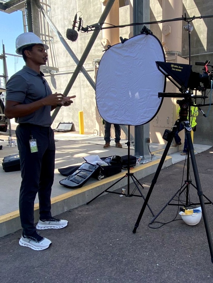 Nicholas Prasad speaking to camera during a content shoot at an industrial facility