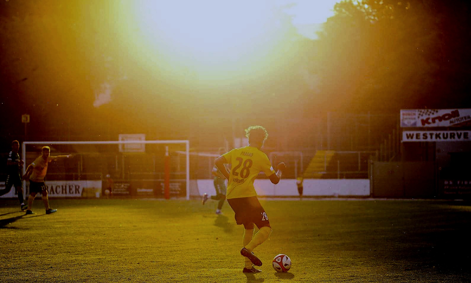 Nicholas Prasad playing professional football, wearing number 28, at golden hour